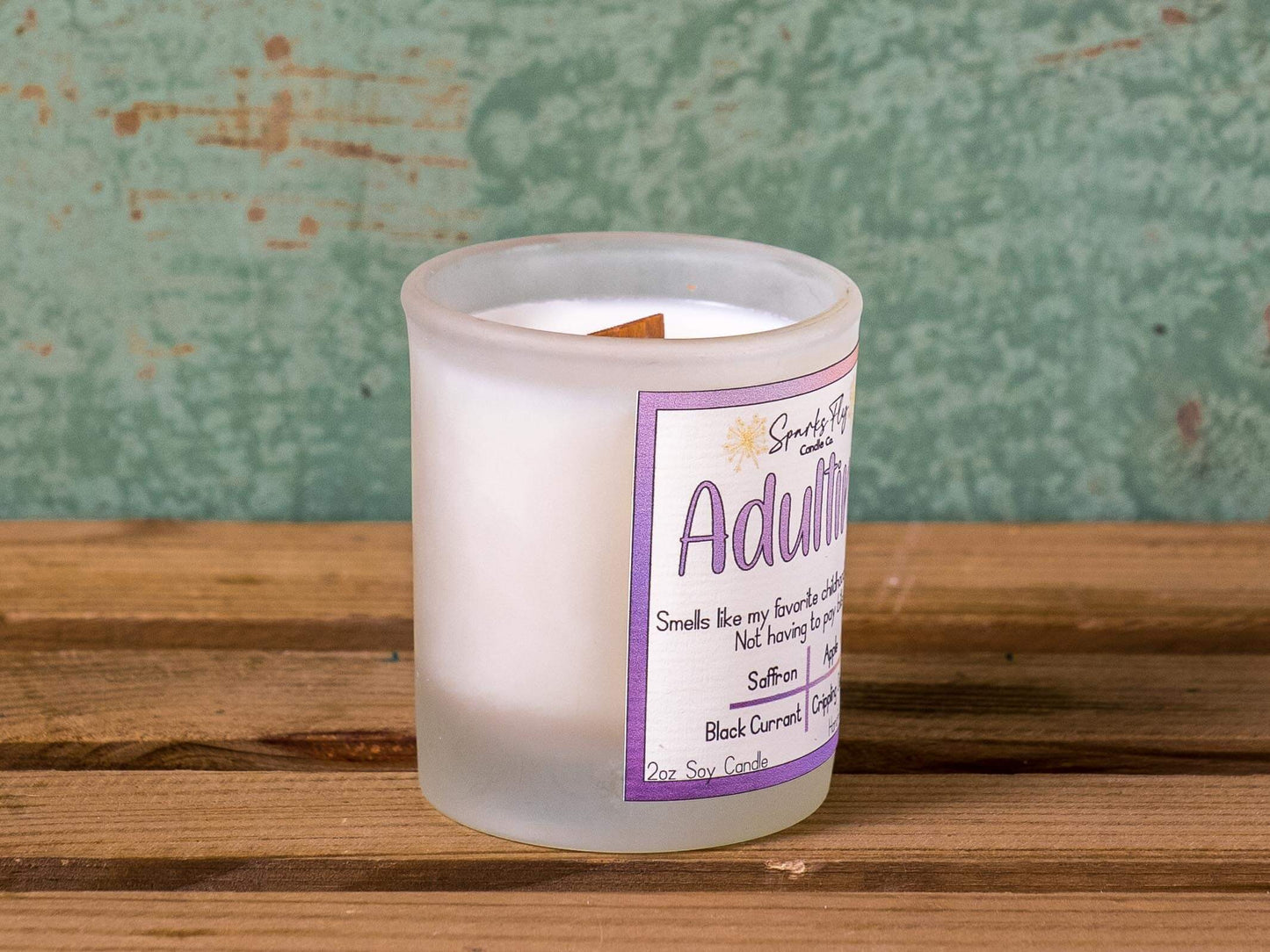 Adulting candle with notes of black currant, absinthe, and apple; capturing childhood memories without bills, satire